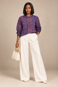 Model wearing Yelé Arewa jacquard sweater with pushed-up sleeves, cream wide-leg trousers and a handbag.