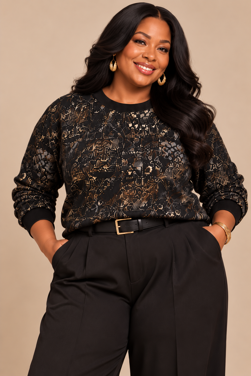 A plus size  woman modeling a black long-sleeve sweater top with an intricate gold and brown African print  pattern, paired with black trousers and a black belt, against a solid beige background.