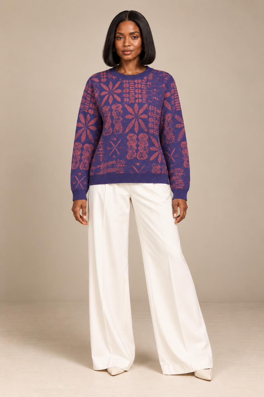 Front view of model wearing Yelé Arewa jacquard sweater untucked, with full-length sleeves and cream trousers.