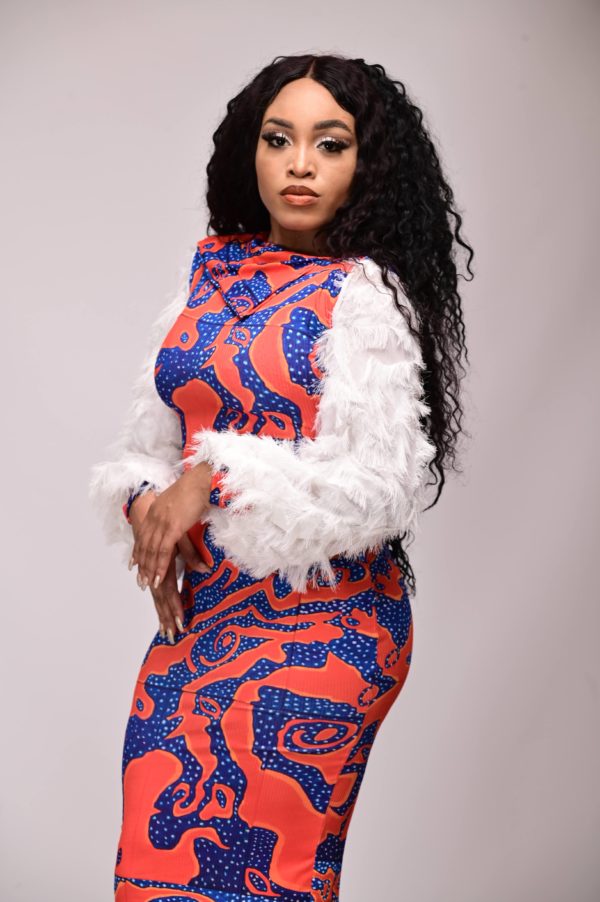 Model wearing afrofuturistic fashion bodycon dress with exclusive ribknit print and feather sleeve detail, available only at YeleStitches.com.