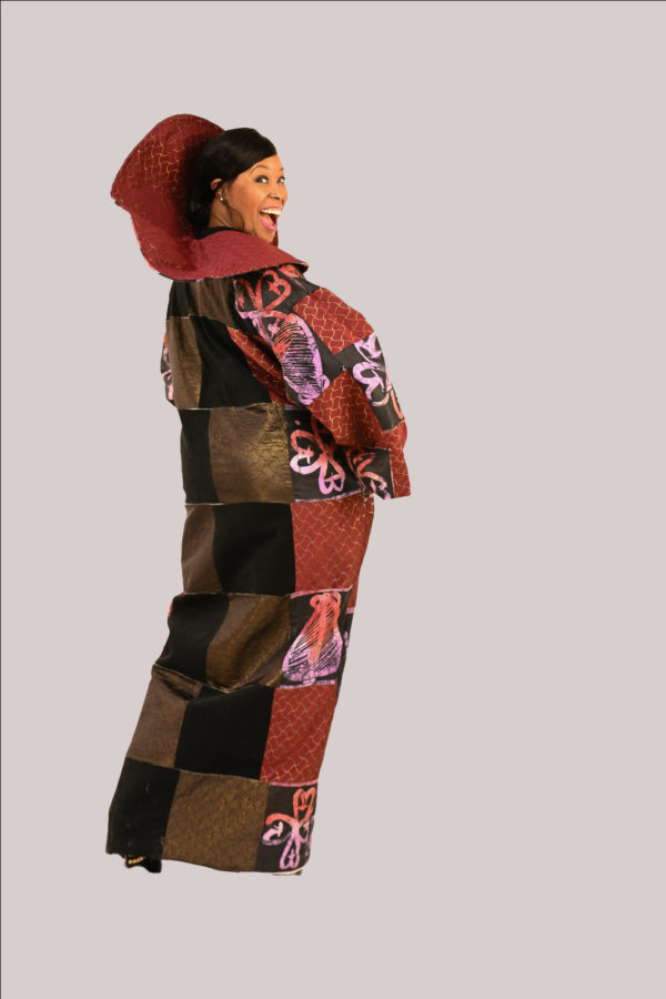Elegant woman in Yele's Adire and velvet suede kimono dress with a wide fan collar and rich cultural motifs. Back view
